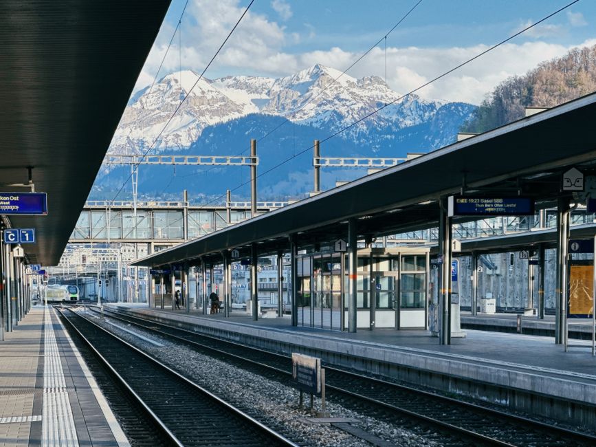 A scenic view of a Swiss train station with the Alps in the background, captured during the day.